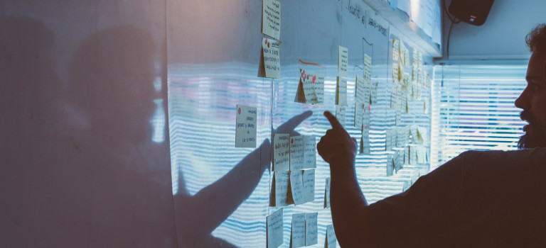 A person planning logistics using a wall of post-it notes