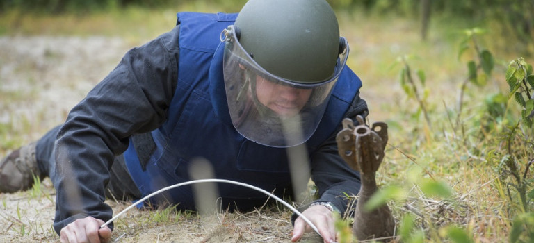 A person in a bomb suit training doing practical explosives tasks