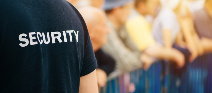 Security officer in front of a crowd of people who are standing behind a barrier